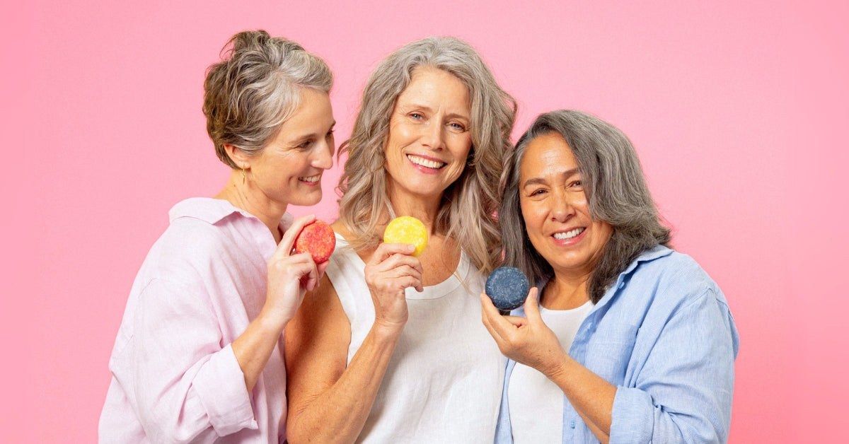 Three women with gray and silver hair laughing and holding Humby shampoo bars
